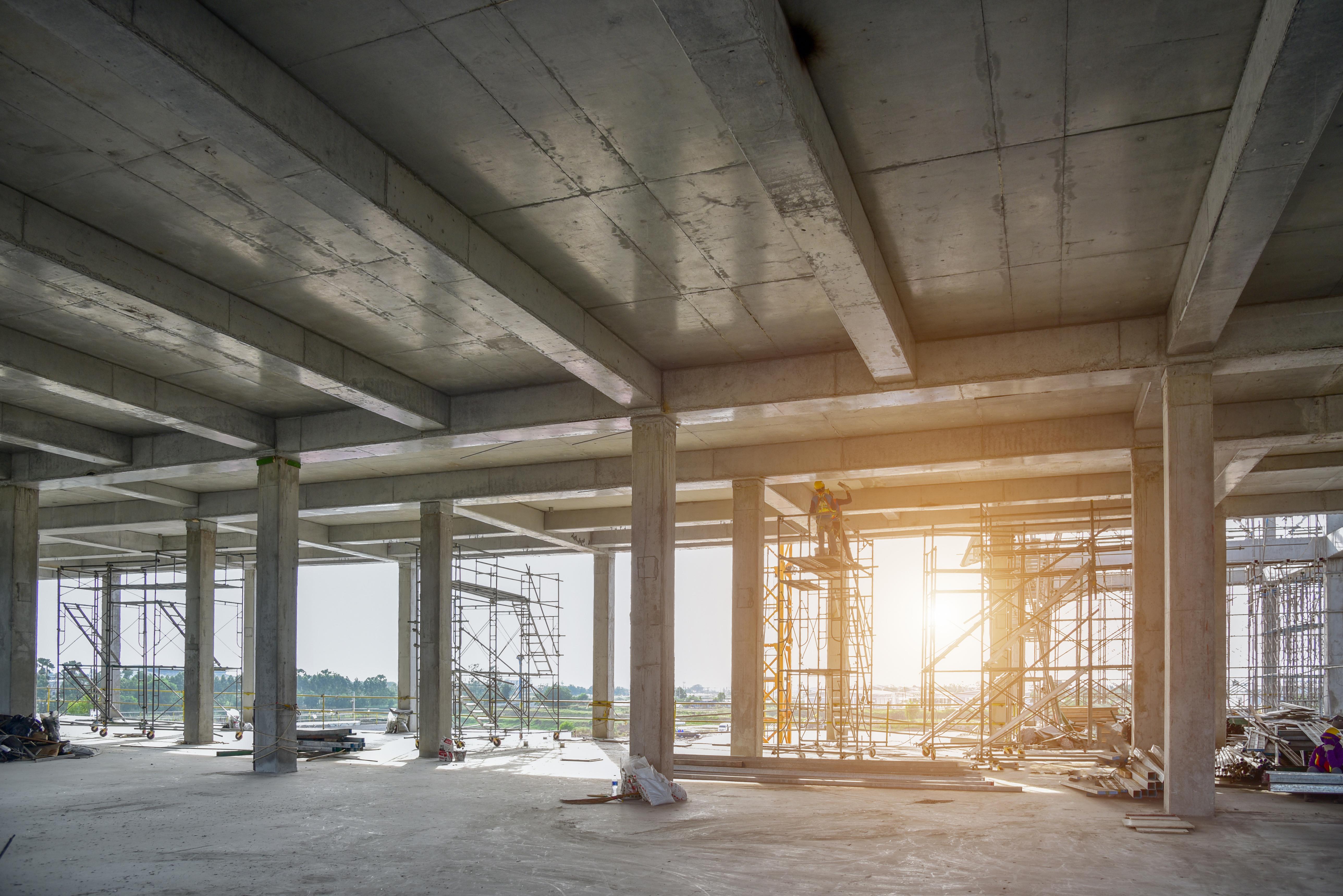 Concrete structural frame of a building under construction, lit by a low sun
