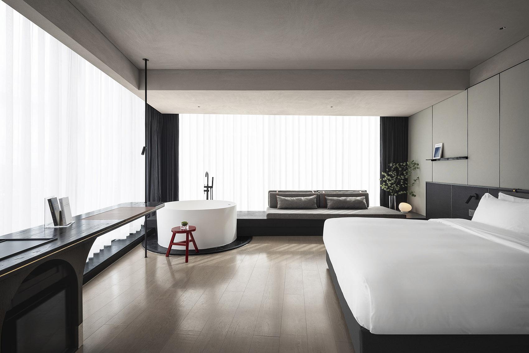 Hotel suite with a freestanding bathtub on a timber floor and full-height glazing